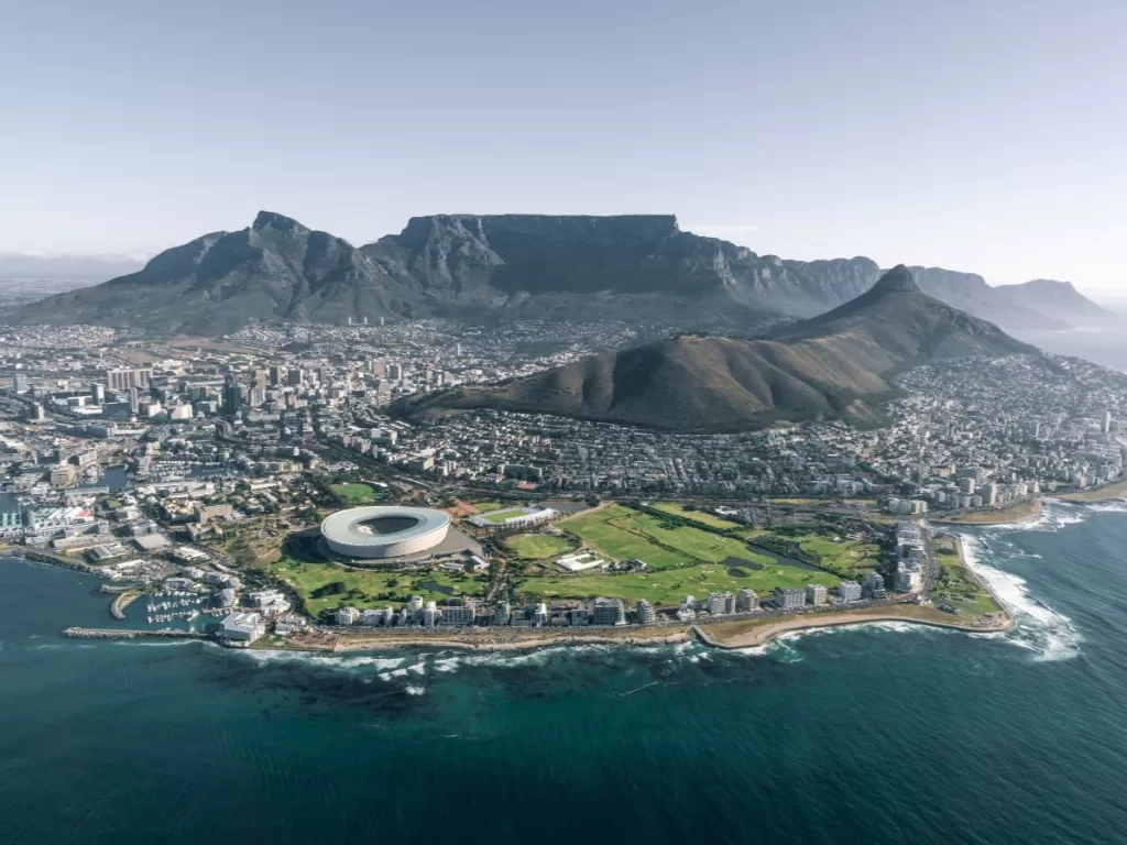 Image of a South African city  with mountains in the background and the ocean in the foreground.