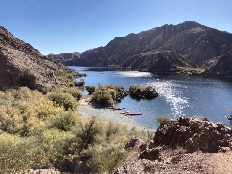 Kayaks on the beach with the Colorado River in the background