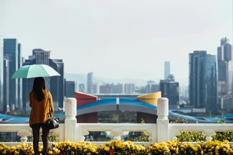 Woman holding an umbrella and looking out at a city view