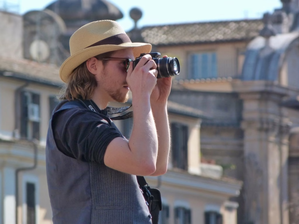 person in black t-shirt and brown fedora hat using black binoculars