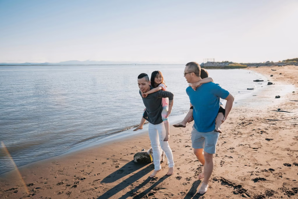 Gay parents with children enjoying a sunny day during a beach walk.