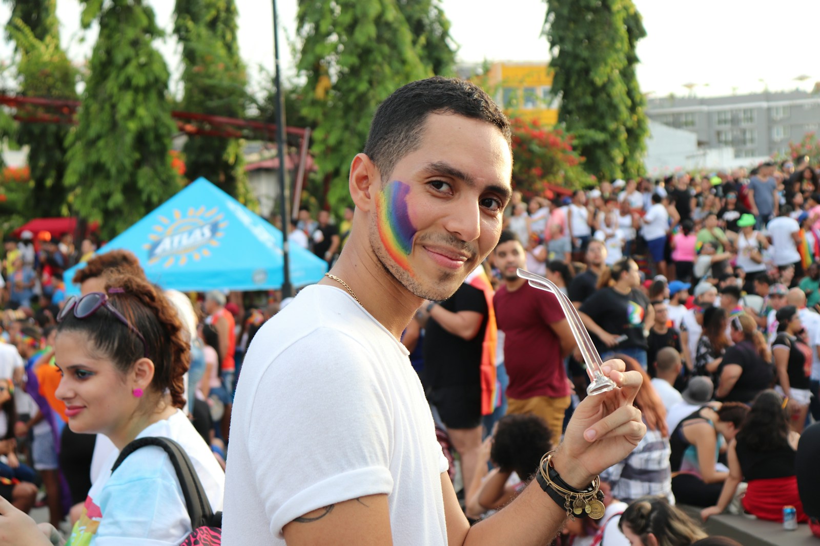 Man in white shirt with rainbow painted on his cheek 