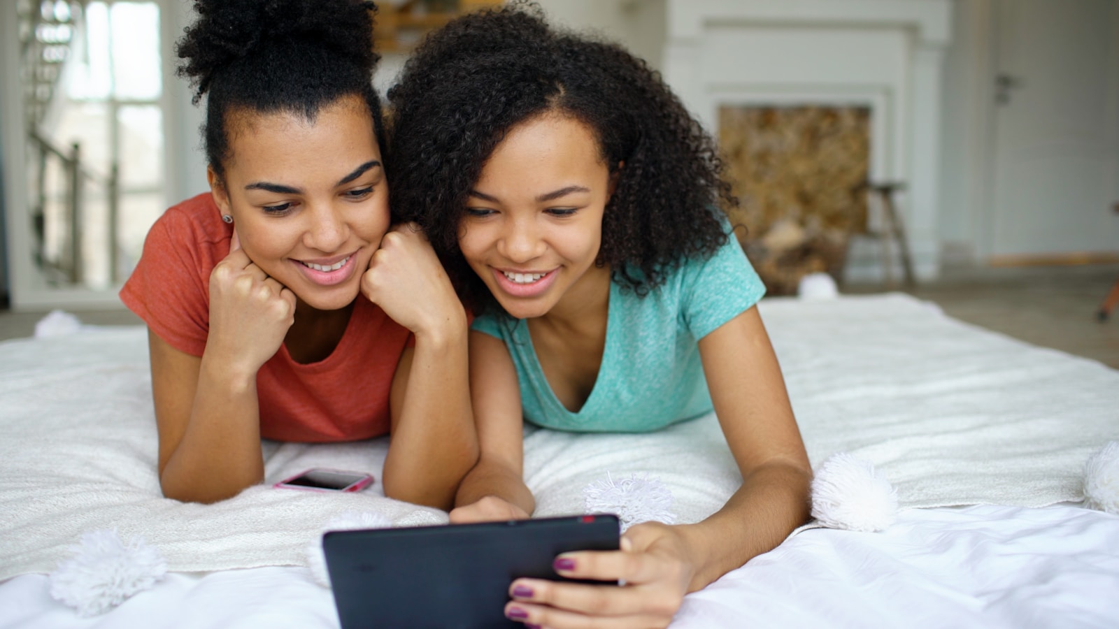 Two smiling young women looking at a tablet