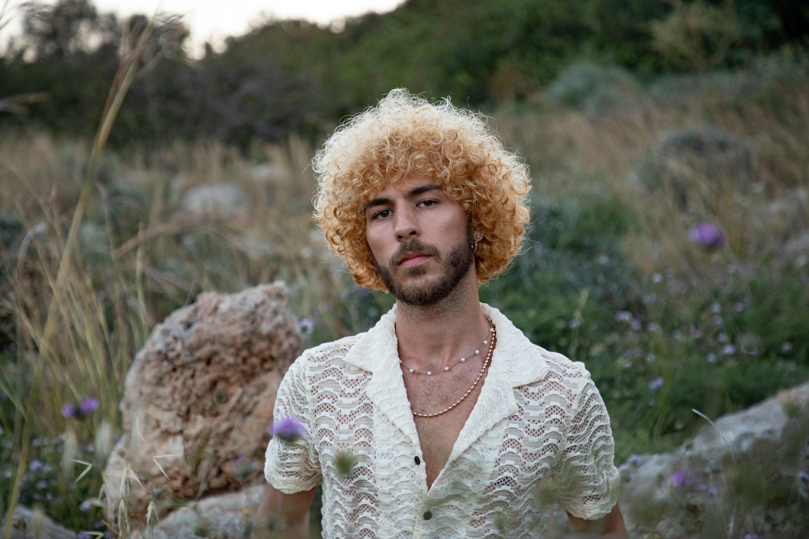 Androgynous person standing in a field.