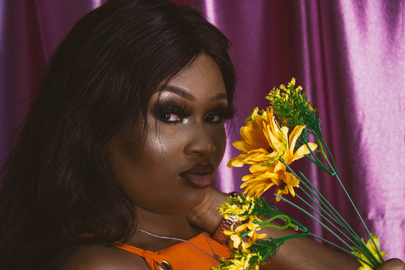 Nigerian woman in orange tank top holding yellow flowers